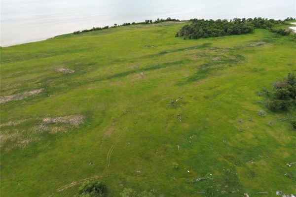 Wide view of a rolling green field with sparse trees and evidence of disturbed ground. - 8 Reykjavik Road, Lake Manitoba Narrows