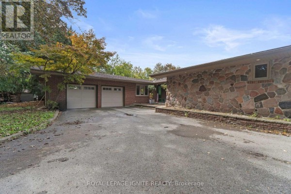 View of the house exterior from the driveway, showing the garage and stone facade. - 8 Ridgevale Drive, Markham