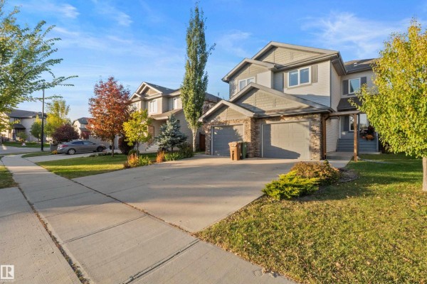 Exterior of duplexes with attached garages and concrete driveways on a sunny day. - 8 Royal St, St  Albert