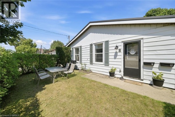 Front exterior with a white door, number 8, and a small outdoor seating area. - 8 Russell Street, Brantford
