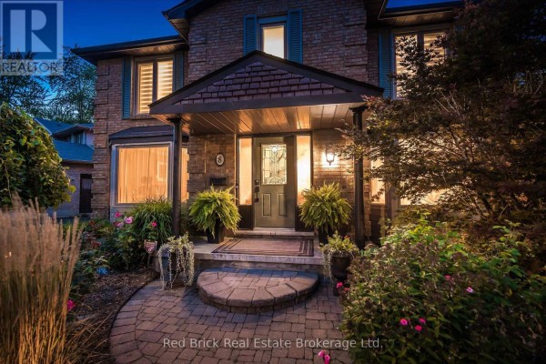 Close-up of the front entrance with a stone pathway, covered porch, and glass-paned door. - 8 Sugarbush Place, Guelph