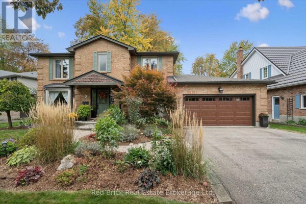 Daytime view of a brick house with a two-car garage and mature landscaping. - 8 Sugarbush Place, Guelph