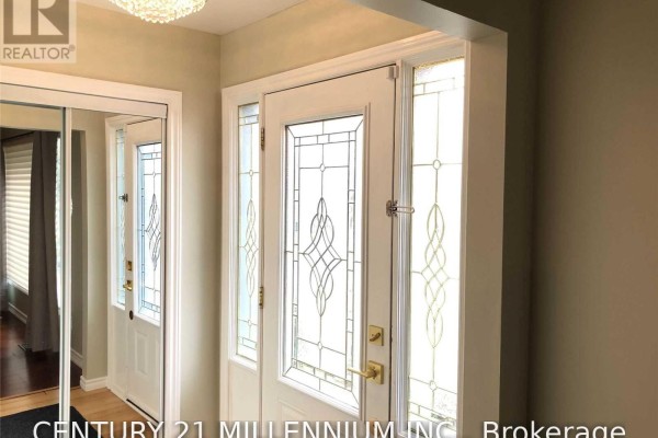 Interior view of a foyer with a white door, stained glass sidelights, and mirrored closet. - 8 Sutherland Avenue, Brampton
