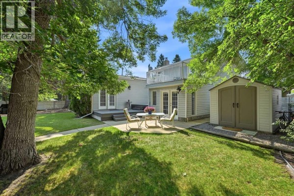 Backyard with a patio, shed, and white double doors leading to the house. - 8 Sydney Close, Red Deer