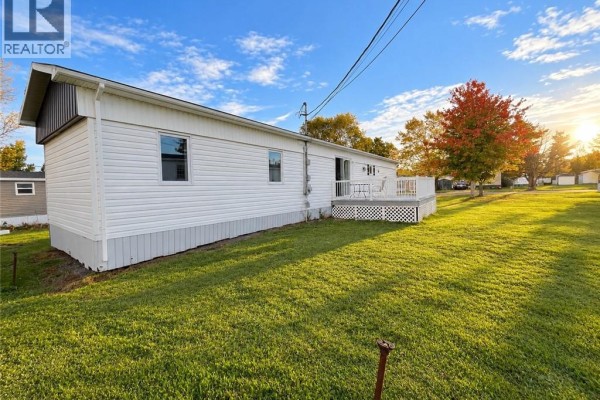 Close-up of the rear deck with white railings, chairs, and a table visible. - 8 Tait Crescent, Moncton
