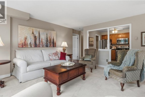 Living room with beige carpet, fireplace, and a view into the kitchen area. - 8 Village Green Boulevard Unit# 510, Hamilton