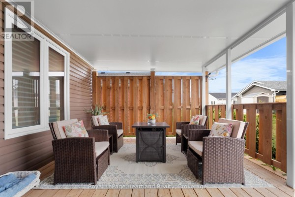 Covered porch with seating area and wooden railing. - 8 Windward Way N, Ashfield Colborne Wawanosh