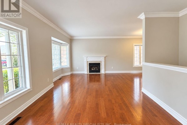 Living room with hardwood floors, a white fireplace mantel, and large bay windows with blinds. - 8 Yorkwood Trail, Brampton