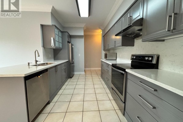 Modern grey kitchen with stainless steel appliances, white countertops, and a double-sink faucet. - 8 Yorkwood Trail, Brampton