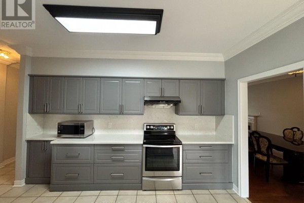 Grey kitchen cabinets with stainless steel appliances, white countertops, and a black stovetop. - 8 Yorkwood Trail, Brampton