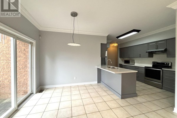 Kitchen with grey cabinets, a large island with a sink, and sliding glass doors to a patio. - 8 Yorkwood Trail, Brampton