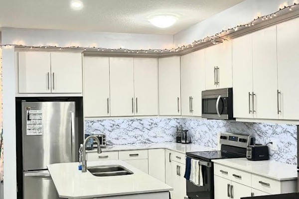 Modern kitchen with white cabinets, stainless steel appliances, and a marble backsplash. - 80 - 1375 Whetherfield Street, London North