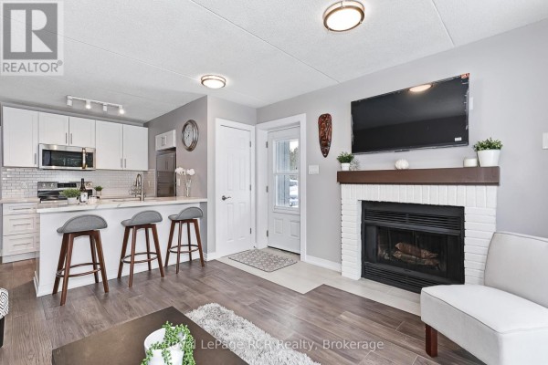 Kitchen with white cabinets, quartz island with three stools, and grey walls. - 80 - 21 Dawson Drive, Collingwood