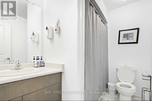 Bathroom with a vanity, toilet, shower curtain, and a framed picture on the wall. - 80 - 4552 Portage Road, Niagara Falls