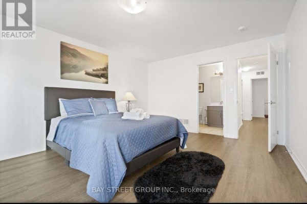 Bedroom with a king-sized bed, landscape artwork, and an entrance to a bathroom. - 80 - 4552 Portage Road, Niagara Falls