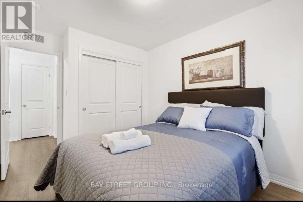 Bedroom with a queen-sized bed, sliding closet doors, and artwork above the headboard. - 80 - 4552 Portage Road, Niagara Falls