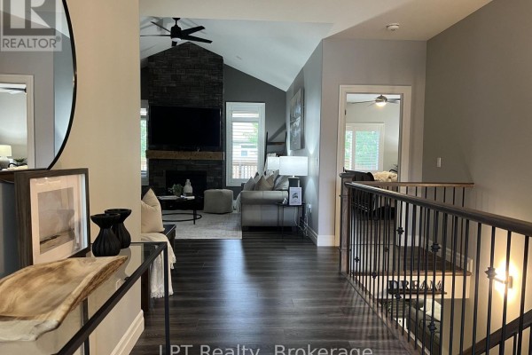 Hallway overlooking a staircase with black railings and a view into the living room. - 80 Ambrosia Terrace, Quinte West