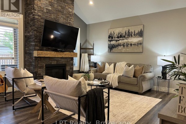 Living room with a floor-to-ceiling stone fireplace, vaulted ceiling, and plush seating. - 80 Ambrosia Terrace, Quinte West