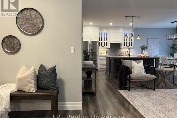 View of the open-concept kitchen with white cabinets and dark grey island from the hallway. - 80 Ambrosia Terrace, Quinte West