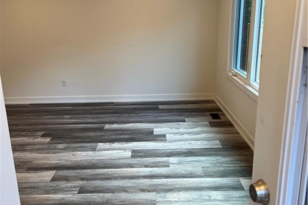 Empty room with light beige walls and wood-look laminate flooring. - 80 Delawana Drive, Hamilton