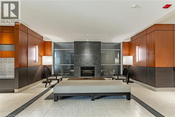 Lobby of the condominium building featuring a modern fireplace, seating, and wood paneling. - 80 Port Street E Unit# 515, Mississauga