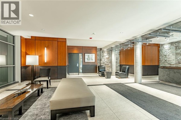 Spacious lobby area with stone accent walls, wood paneling, seating, and mailboxes. - 80 Port Street E Unit# 515, Mississauga
