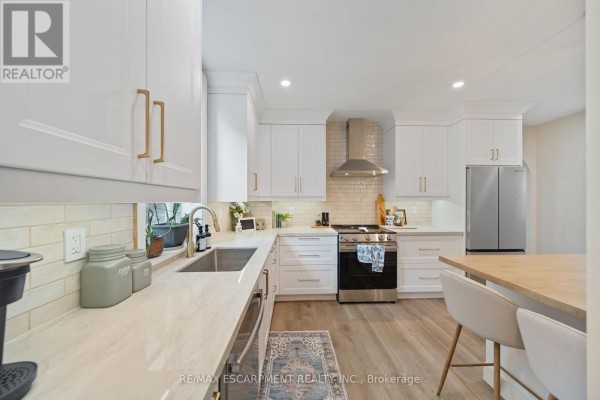 Modern kitchen with island, white cabinets, stainless steel appliances, and quartz countertops - 80 Sarah Street Brant