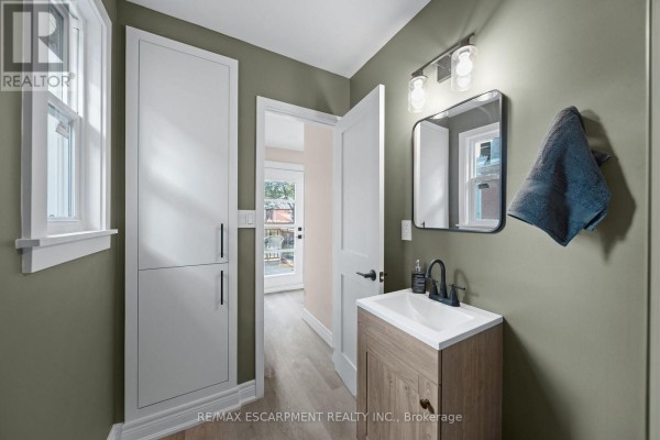 Bathroom vanity with wood cabinet, vessel sink, black faucet, mirror, and tall storage cabinet - 80 Sarah Street Brant