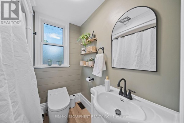 Bathroom with dual-flush toilet, arched mirror, and floating shelves - 80 Sarah Street Brant
