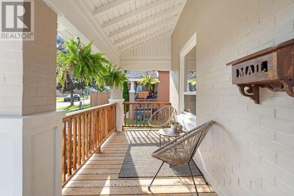 Close-up of the wooden porch with two modern chairs, a small table, and a mailbox. - 80 Sarah Street, Brant