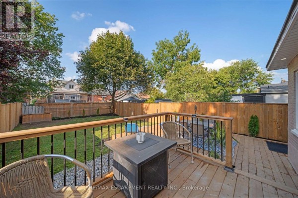 Wooden deck with fire pit table and chairs overlooking backyard - 80 Sarah Street Brant