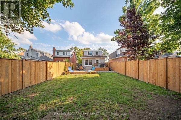 Backyard with wooden fence, deck, lounge chairs, and lawn - 80 Sarah Street Brant