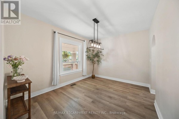 Dining room with wood-look floors, modern chandelier, and window view - 80 Sarah Street Brant