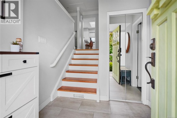Entranceway with light grey walls, wooden stairs, and a mirrored closet. - 800 Alvarado Terr, Saanich
