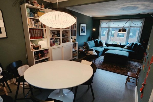 Dining area with a white round table and chairs, adjacent to a living room and bookshelves. - 800 Davenport Road, Toronto