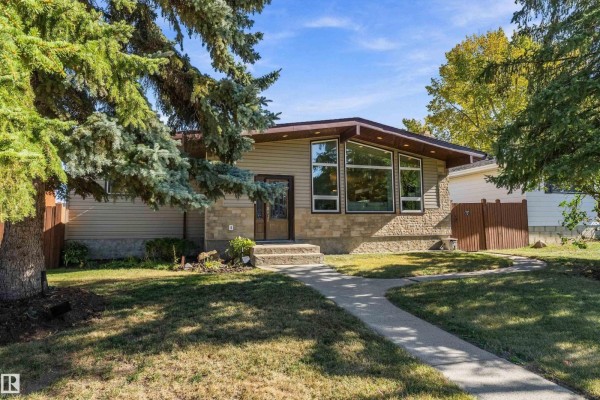 View of a house exterior with beige siding, stone accents, and large front windows. - 800 Lee Ridge Rd Nw, Edmonton