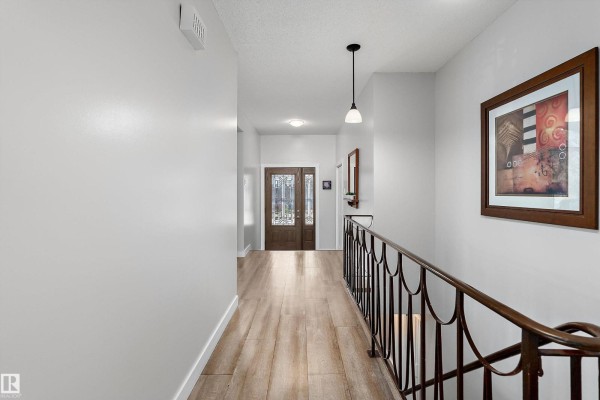 Interior hallway with light grey walls, wood-look flooring, and a view of the front door. - 800 Lee Ridge Rd Nw, Edmonton