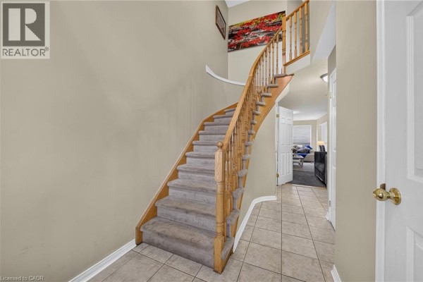 Hallway facing a curved staircase with carpeted steps and a wooden banister. - 800 Paramount Drive Unit# 77, Stoney Creek