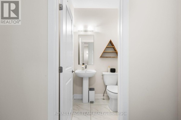 Powder room with a white pedestal sink, toilet, and marble-look tile flooring. - 800 Solarium Avenue, Ottawa