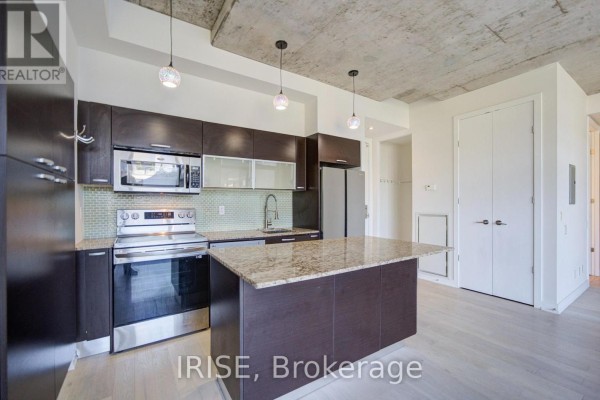 Kitchen details including stainless steel stove, dishwasher, granite island, and light wood flooring. - 801 - 10 Morrison Street, Toronto