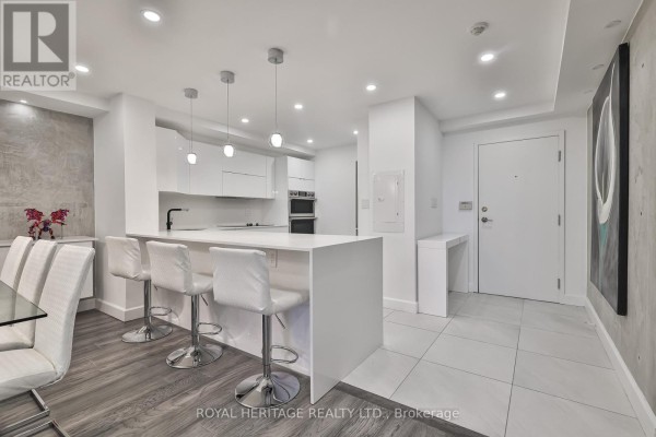 Bright kitchen featuring white cabinetry, island seating, and stainless steel appliances - 801 - 10 Torresdale Avenue, Toronto