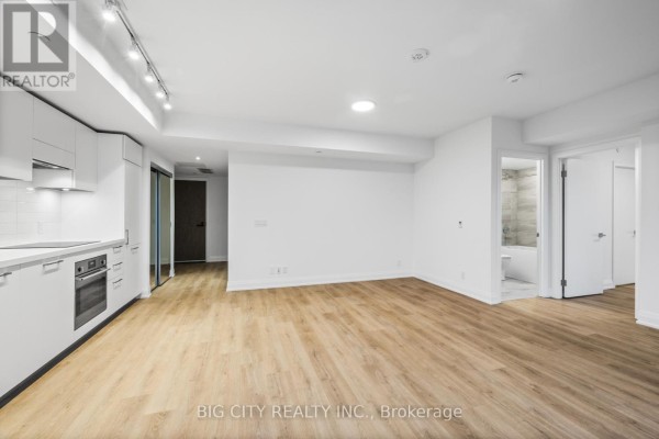 Open concept living space with modern kitchen and light wood flooring. - 801 - 36 Brentcliffe Road, Toronto