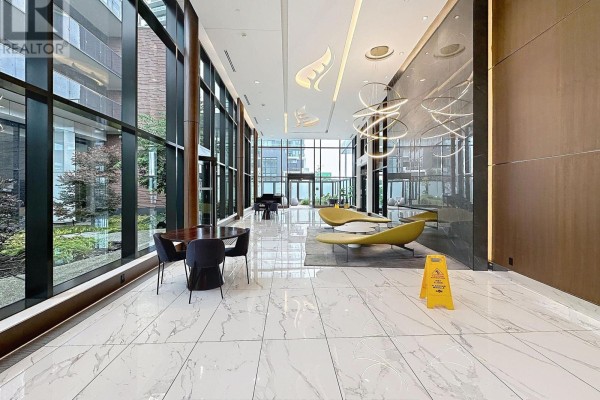 Lobby with seating area, modern chairs, and large windows overlooking greenery. - 801 - 95 Mcmahon Drive, Toronto