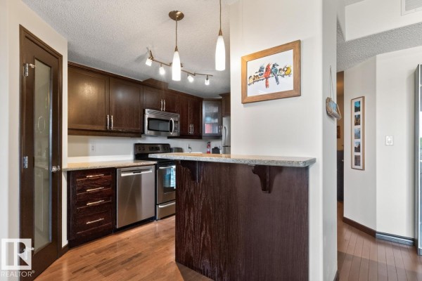 Kitchen with dark wood cabinets and granite countertops. - #801 9707 106 St Nw, Edmonton
