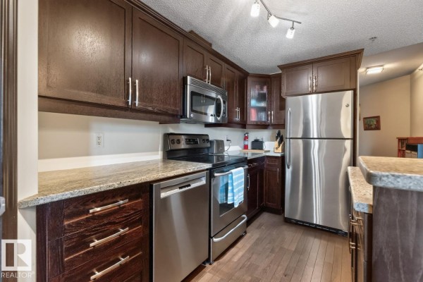 Kitchen with stainless steel appliances and dark wood cabinets. - #801 9707 106 St Nw, Edmonton