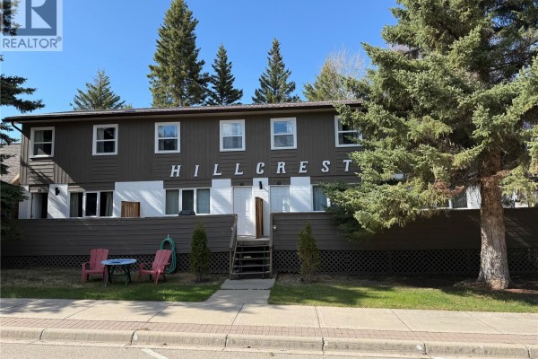 Front view of a two-story building with brown siding and green accents, featuring a porch and snowy surroundings. - 801 Lakeview Drive, Prince Albert National Park