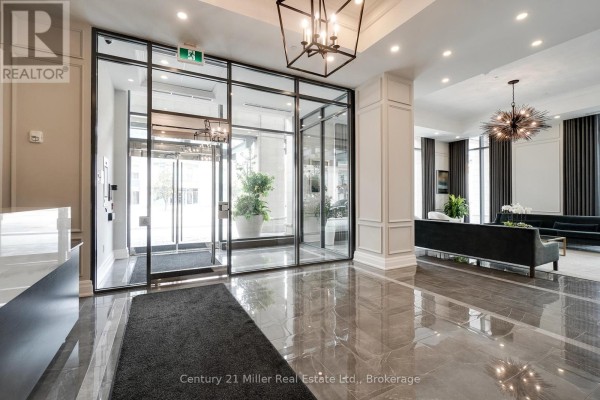 Modern lobby entrance with glass doors, dark grey floors, and decorative molding on walls. - 802 - 2060 Lakeshore Road, Burlington