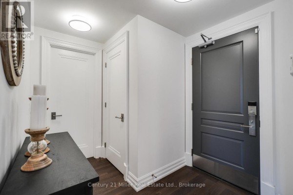 Apartment entryway with a dark grey door, white doors, and a black console table with candles. - 802 - 2060 Lakeshore Road, Burlington