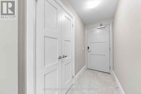 Apartment entrance hallway with light grey walls, tiled floor, and white double doors. - 802 - 73 Arthur Street, Guelph