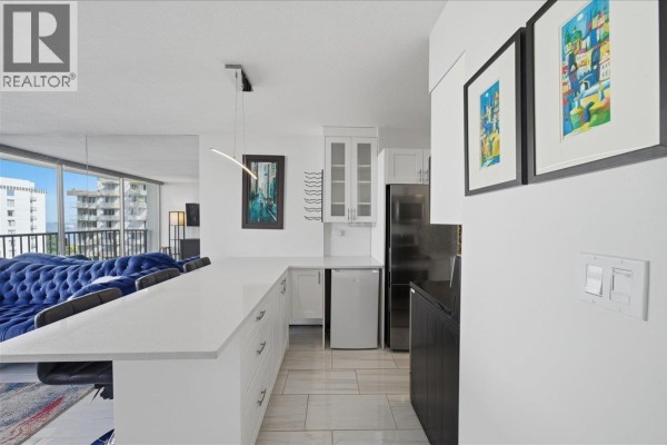 Open concept living space with white kitchen island, cabinetry, and black appliances. - 802 1251 Cardero Street, Vancouver